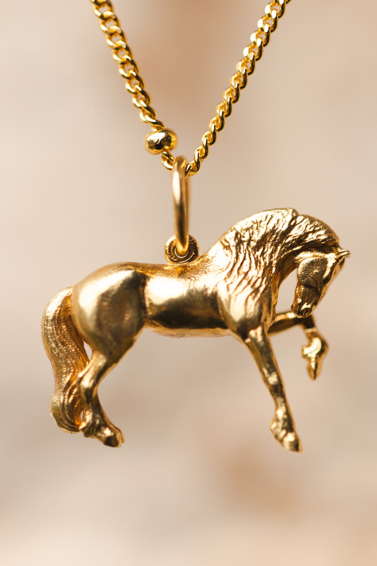 Capturing the powerful elegance and flowing grace of the Friesian horse  this is the perfect horse gift for friesian horses fans. Friesian Horse Pendant is a gold pendant necklace. The pendant is shaped like a horse in mid-stride, with detailed features such as its mane and tail. The necklace chain is also gold and has a series of small, rounded beads interspersed along its length.