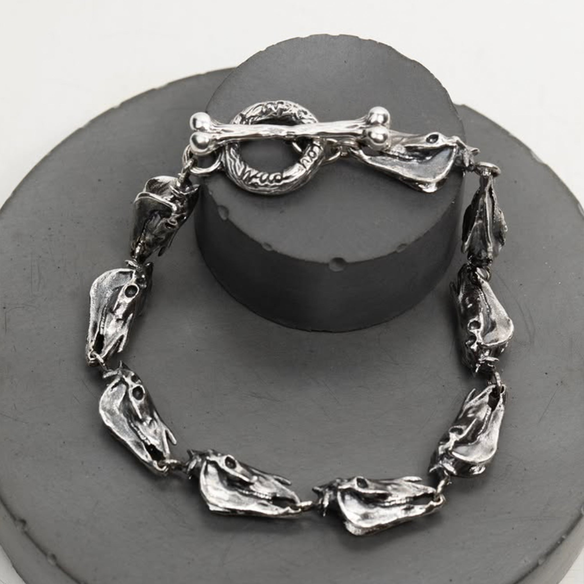 Detailed horse jewelry photo of the chunky silver horse bracelet, showing the individual linked horse skull charms and the sculptural bone.