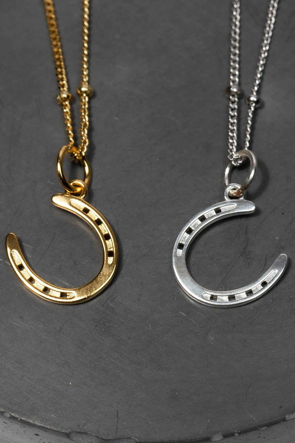 A pair of gold and silver horseshoe necklaces, symbolizing luck and elegance in a stylish design.
The necklace chain is also gold and silver respectively, chain has a series of small, rounded beads interspersed along its length . Crafted from high-quality gold and silver, ideal for horse fans, pony lovers, show jumping, equestrian life and fans of equestrian inspired jewelry, gold girls and silver girls.