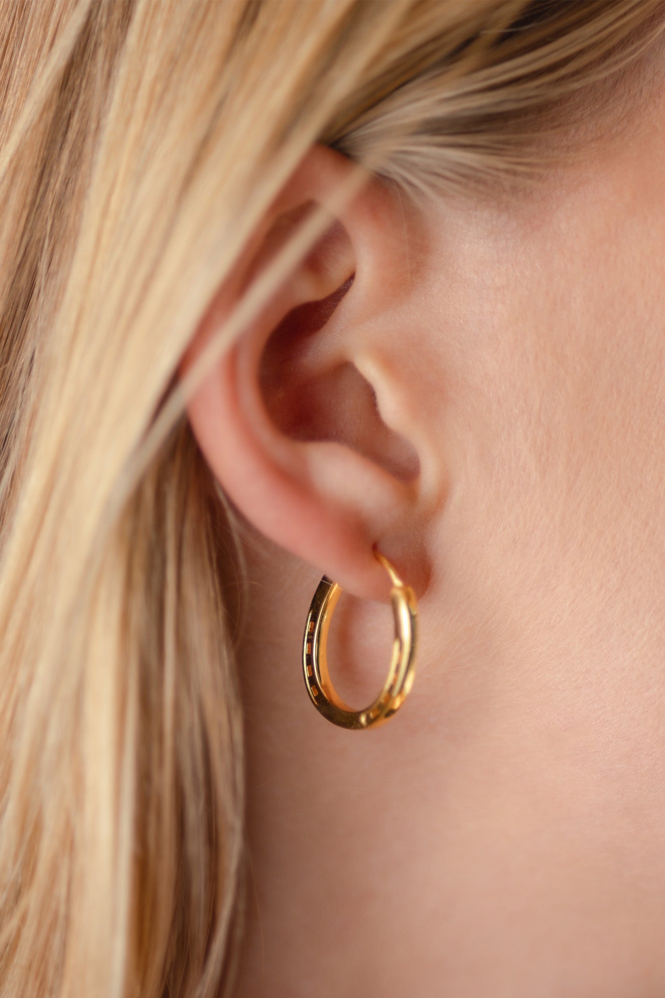 A close-up of a pair of elegant gold horseshoe earrings, perfect birthday present ideas for horse lovers, horse girls, cowgirls.