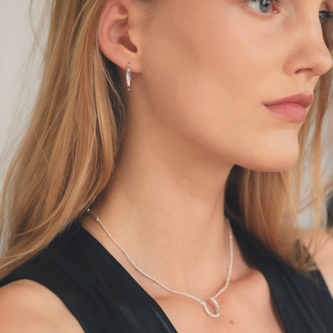 A close-up of a pair silver horseshoe earrings, perfect present ideas for horse lovers.
