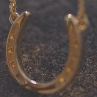 An elegant gold necklace featuring a snaffle bit charm.