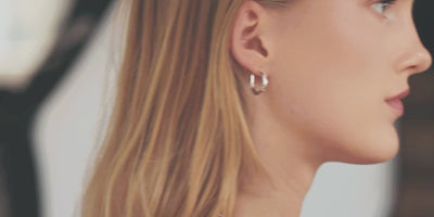 A product video showcasing a model wearing delicate silver horseshoe earrings