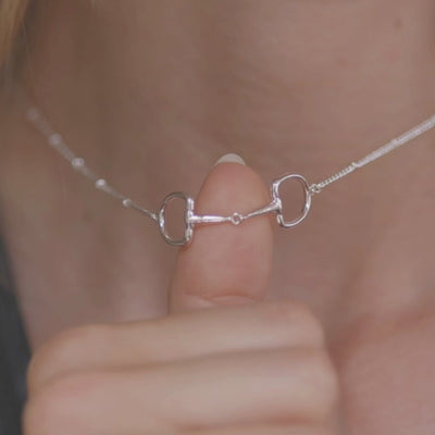 A beautiful silver necklace with a snaffle bit pendant and a lobster clasp.