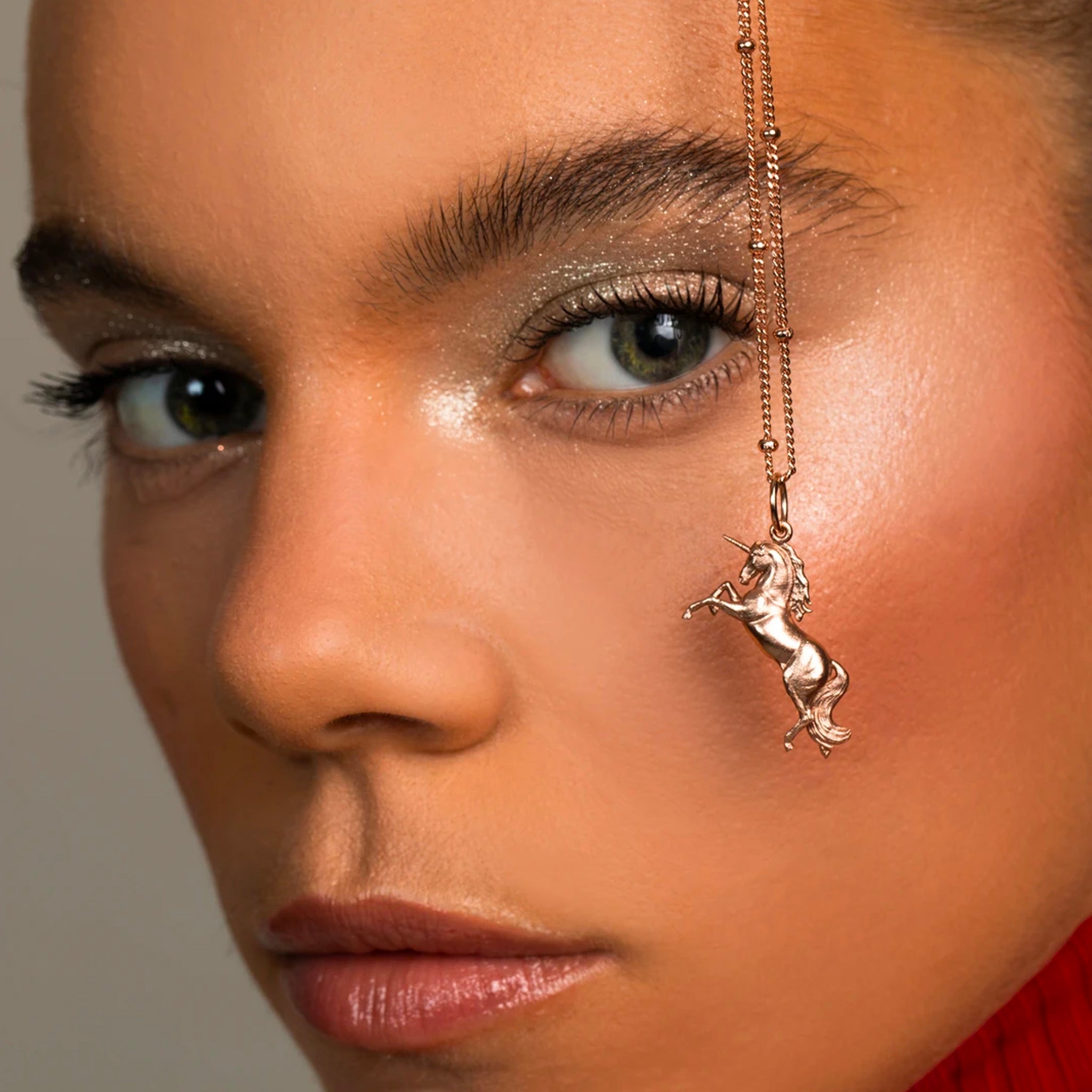 A close-up view of a small, detailed unicorn pendant crafted in rose gold vermeil, hanging from a delicate chain, representing the Mini Unicorn pendant necklace.